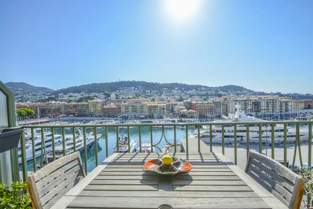 Photo depuis un balcon d'appartement, devant une table et avec vue sur le port de Nice